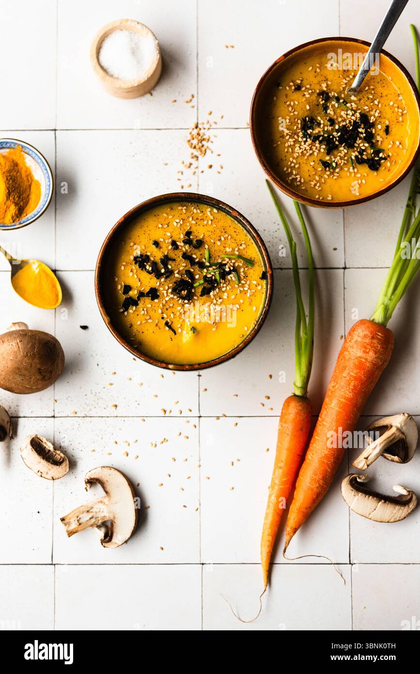 Zuppa calda e cremosa di zucca guarnita con semi di sesamo e alghe wakame. Impreziosito da curcuma, funghi portobello, carote e altri vivaci lingotti Foto Stock