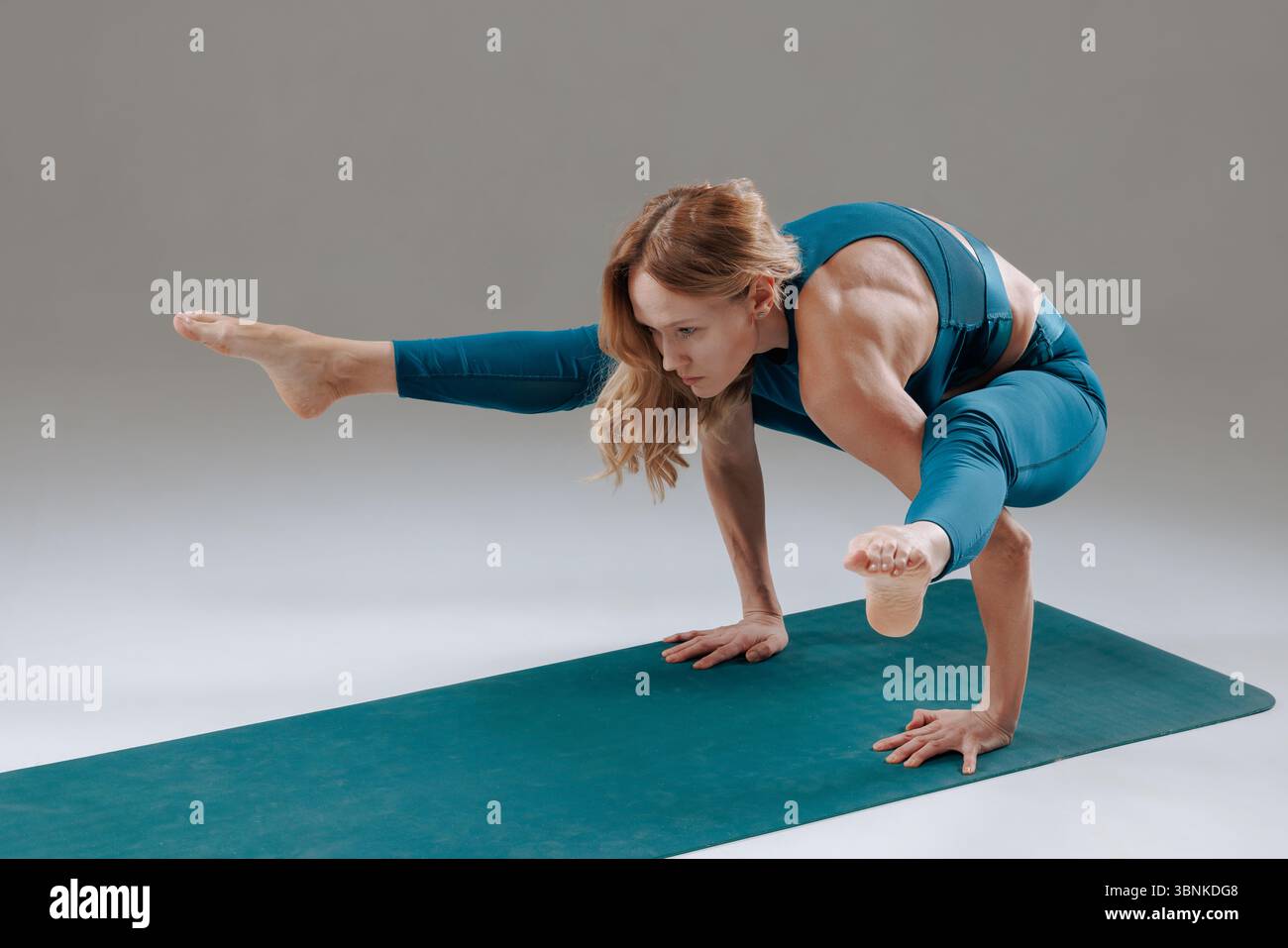 Donna forte e flessibile in posizione avanzata sul braccio per yoga in interni, che mostra la forza della concentrazione e la consapevolezza del corpo Foto Stock