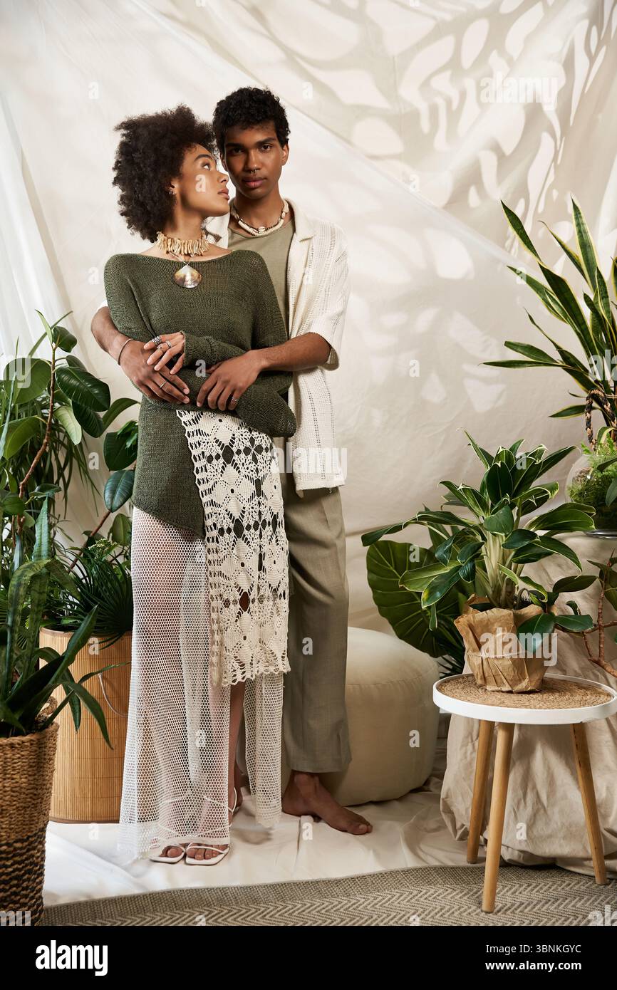 Una giovane coppia abbraccia il verde vibrante, trasudando amore e stile. Foto Stock