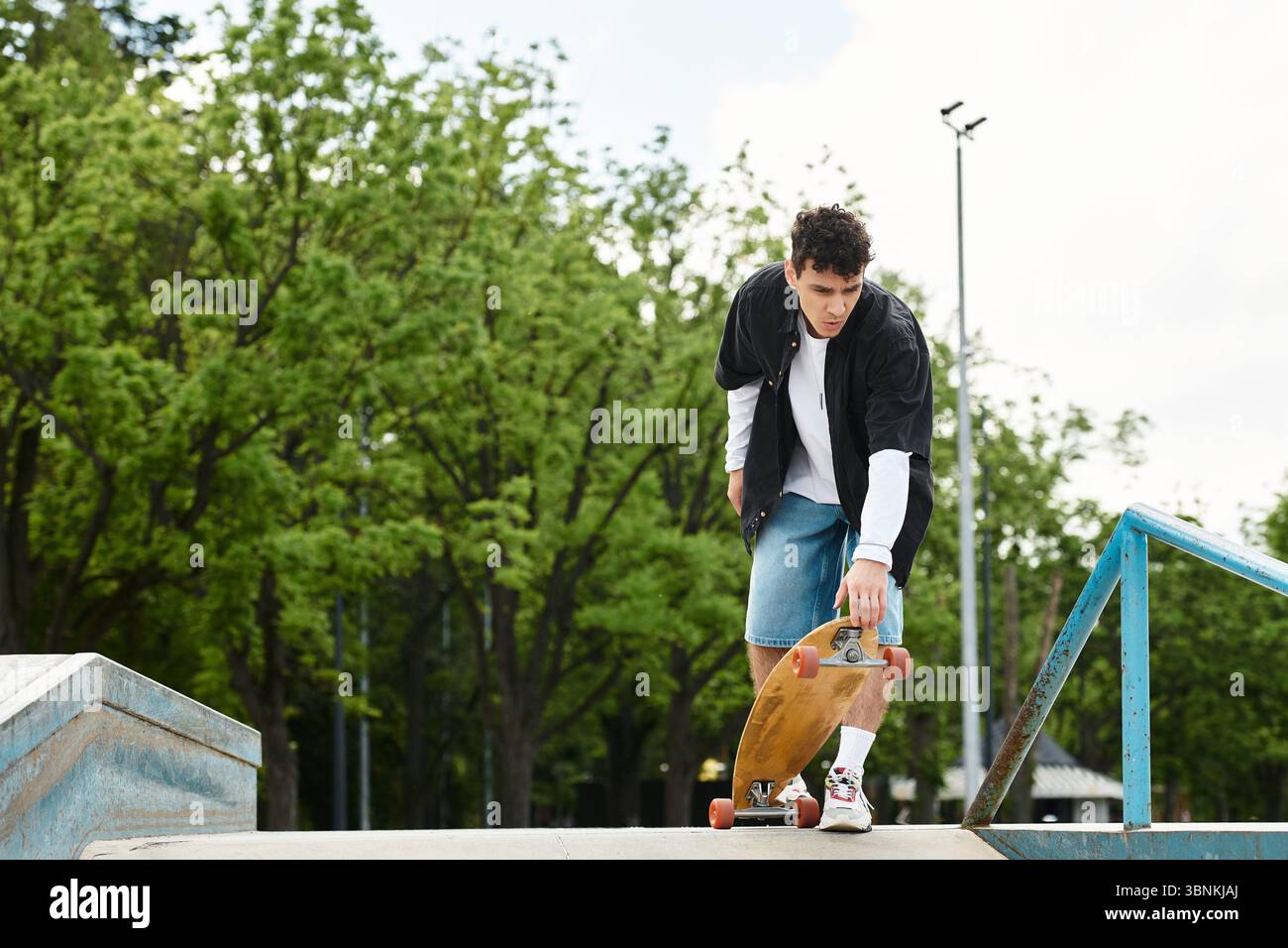 Un giovane cavalca abilmente il suo skateboard in un parco vivace pieno di verde e sole. Foto Stock