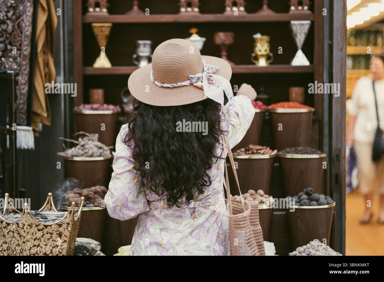 Una donna turistica che acquista spezie al mercato delle spezie al Seef di Dubai, Emirati Arabi Uniti, con bancarelle tradizionali e visitatori che esplorano il mercato locale Foto Stock