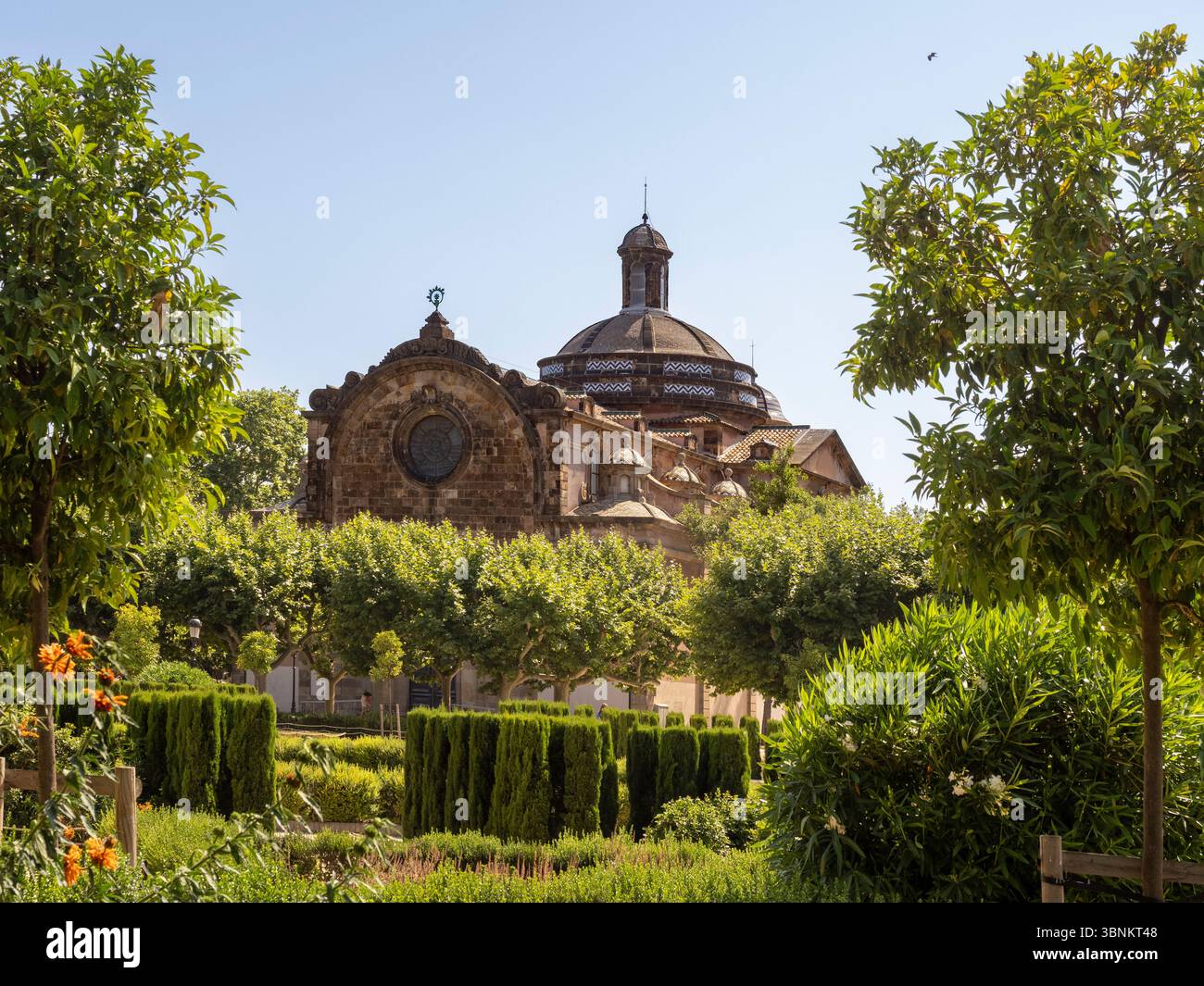 La cupola della Chiesa Parrocchiale militare della Cittadella del XVIII secolo sorge sopra i lussureggianti e formalmente disposti alberi del Parc de la Ciutadella a Barcellona Foto Stock