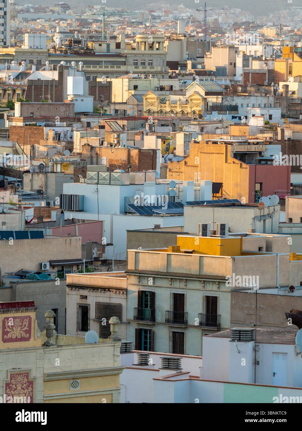 Una vista dettagliata dei tetti densi e stratificati di uno storico quartiere di Barcellona, immersi nel caldo bagliore del tramonto. Spagna. Foto Stock