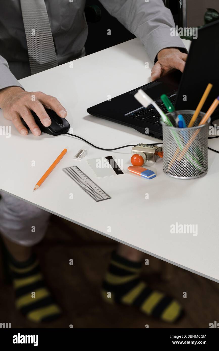 Dipendenti che lavorano da casa telelavoro davanti a un computer portatile con postazione di lavoro improvvisata e codice di abbigliamento Foto Stock
