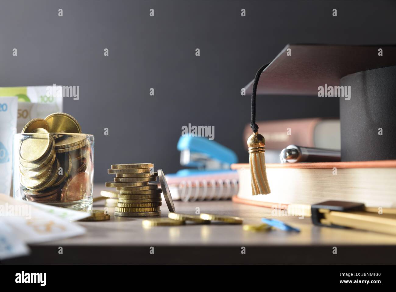 Costo elevato del concetto di istruzione con denaro e forniture educative su tavola di legno e sfondo oscuro isolato. Vista frontale. Foto Stock