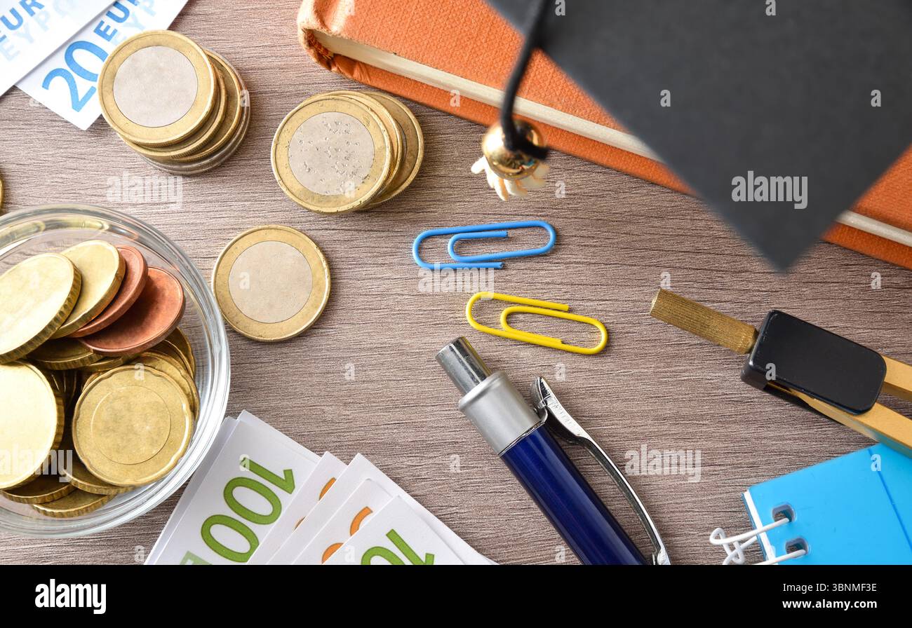 Concetto di spesa per l'istruzione con denaro e forniture educative su tavola di legno. Vista dall'alto. Foto Stock