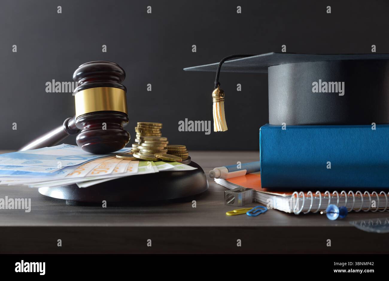 L'istruzione costa il concetto di legge con soldi su una base di legno piena di soldi e forniture scolastiche con un cartello in cima a un tavolo di legno e isolato Foto Stock
