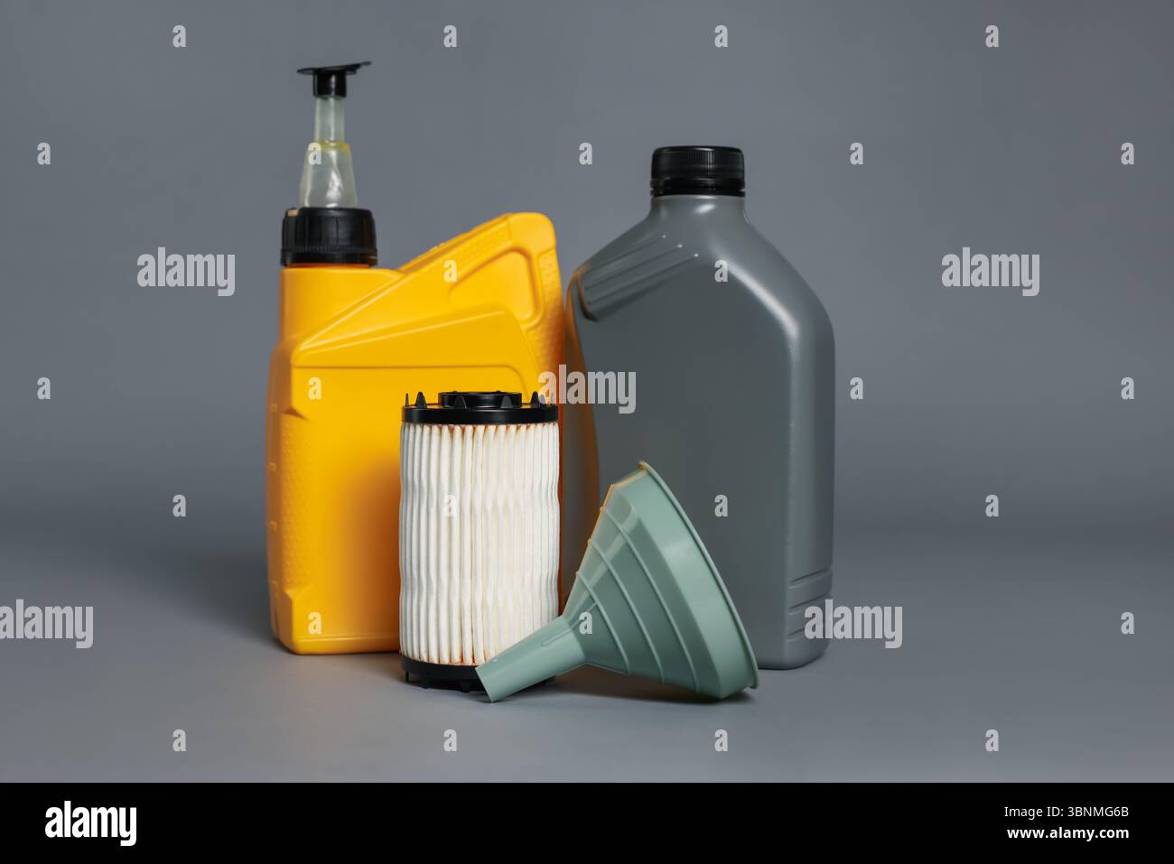 Olio motore in contenitori in plastica, filtro e imbuto su sfondo grigio Foto Stock