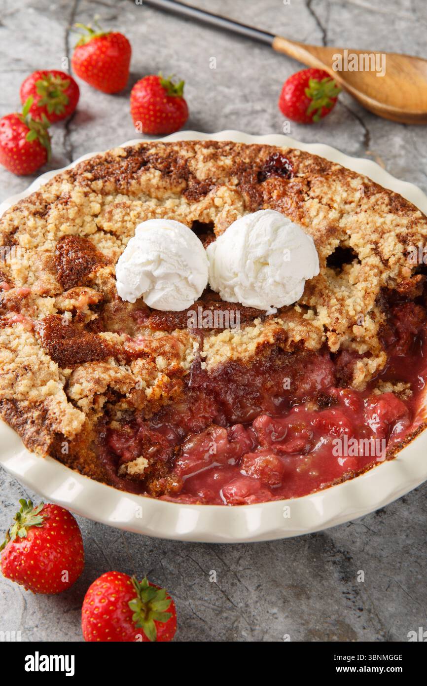Ciabattino alle fragole al cioccolato con gelato alla vaniglia da primo piano nel piatto da forno sul tavolo. Verticale Foto Stock