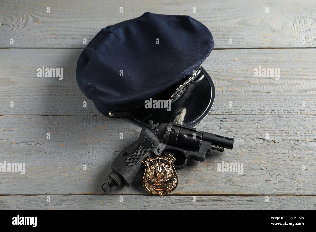 Cappellino, pistola e distintivo della polizia sul tavolo in legno grigio, sopra la vista Foto Stock