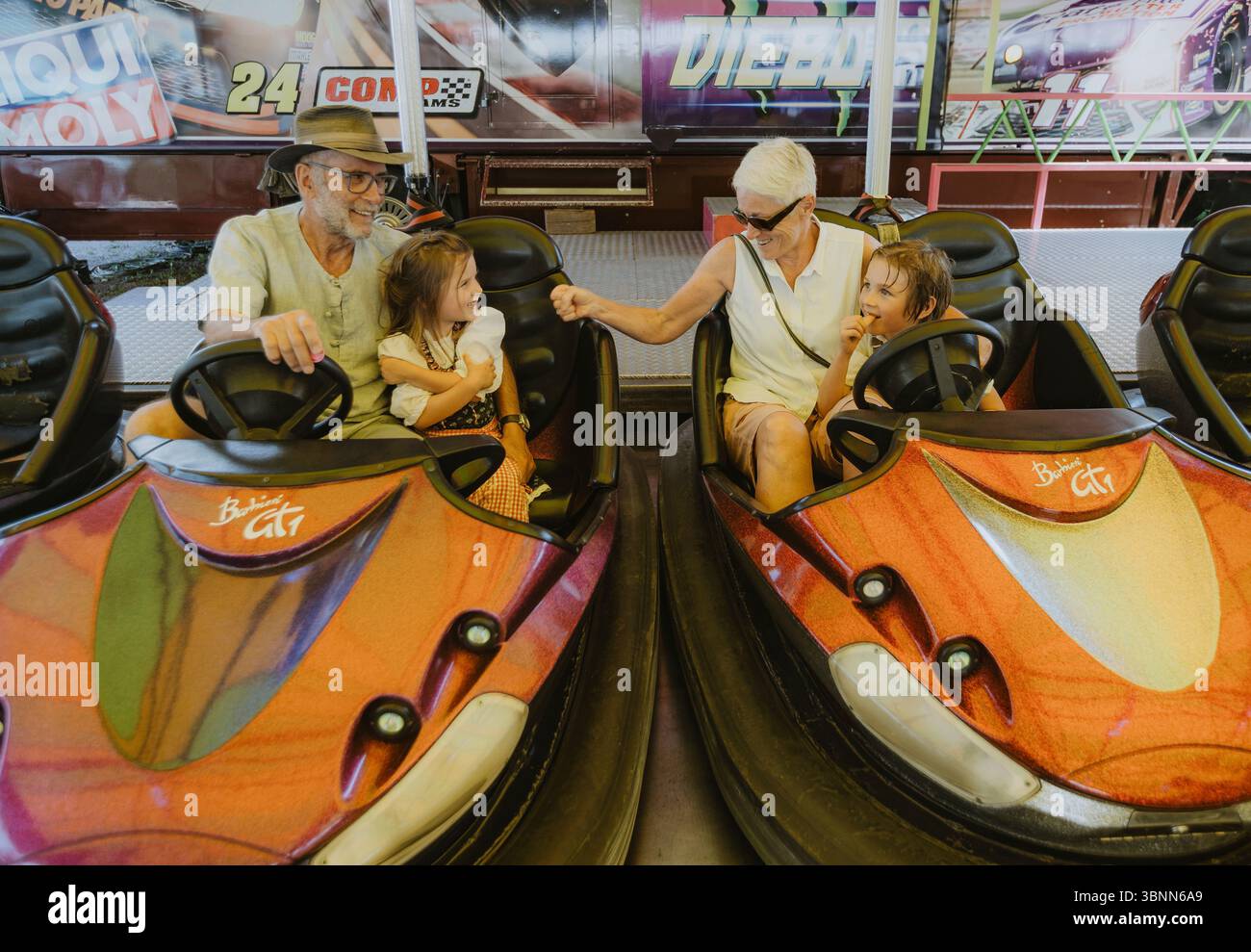 Nonni con nipoti in un autoscontro a un festival popolare Foto Stock