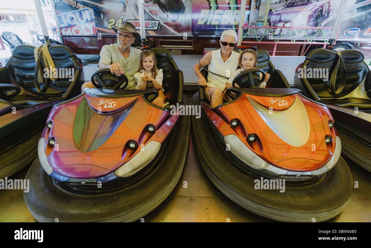 Nonni con nipoti in un autoscontro a un festival popolare Foto Stock