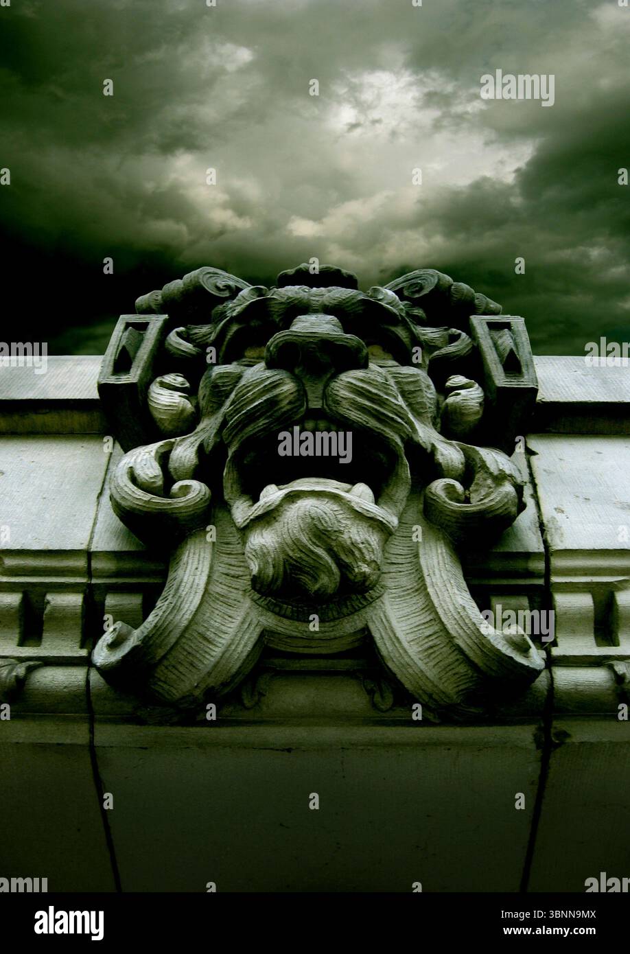 Una faccia demoniaca di pietra su un ripiano, cielo nuvoloso Foto Stock