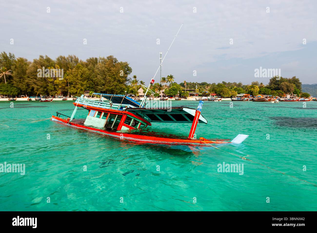 Barca a coda lunga affondata, una nave naufragata nel mare verde smeraldo vicino alla costa dell'isola di Koh Lipe, Thailandia. Foto Stock