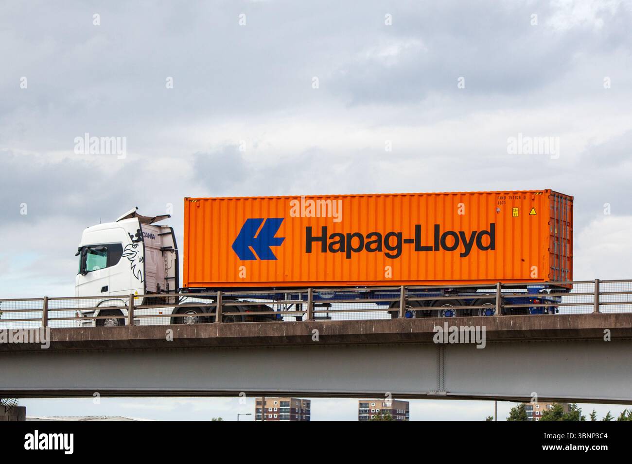 Il camion articolato bianco Scania con un container multimodale arancione Hapag-Lloyd su un rimorchio scheletrico attraversa un ponte prefabbricato di cemento a Tamworth, U Foto Stock