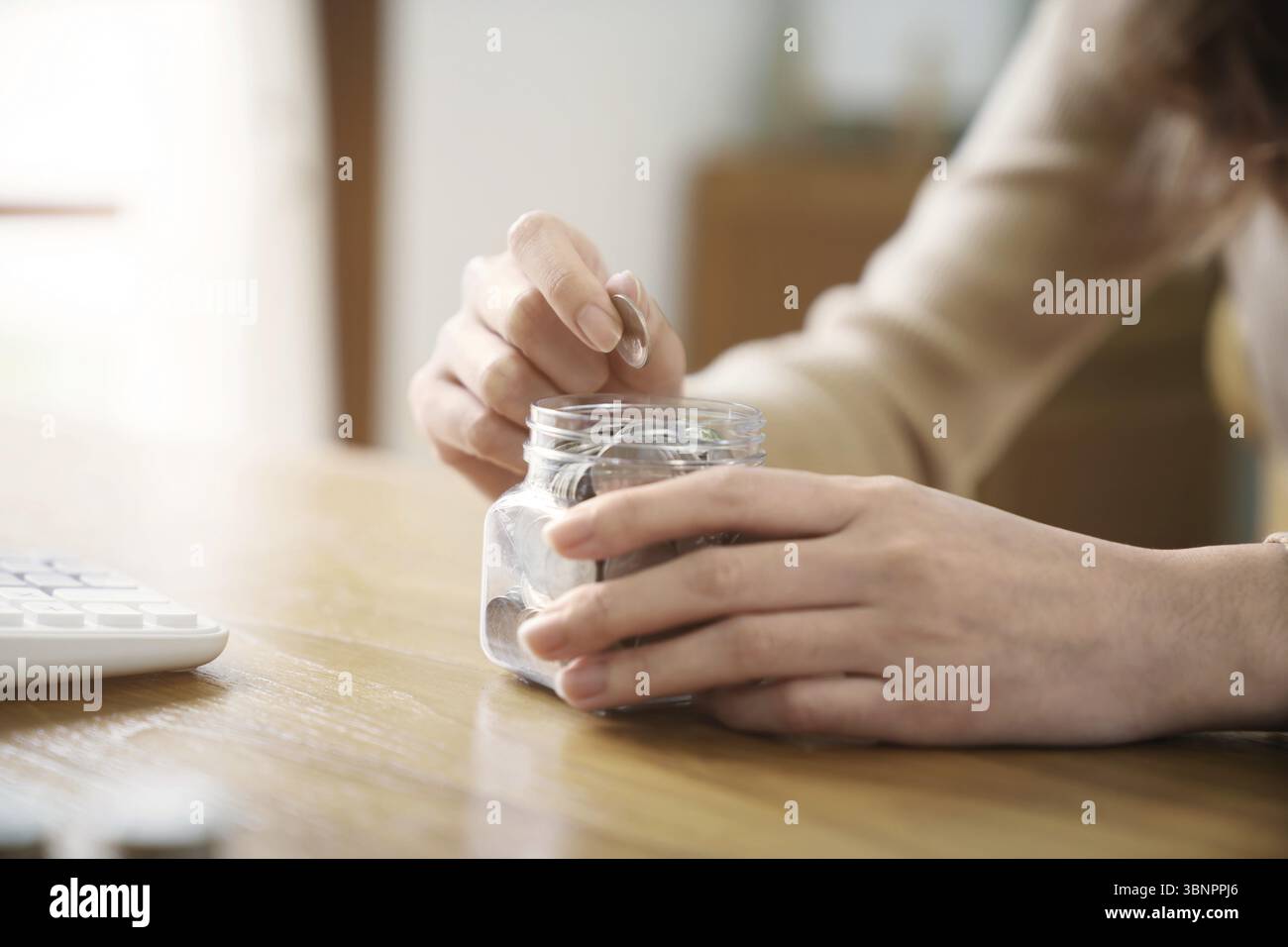 Concetto di risparmio crescente. Risparmiare denaro mettendo a mano monete moneta banconote in brocca vetro pianificazione contabile finanziaria Foto Stock