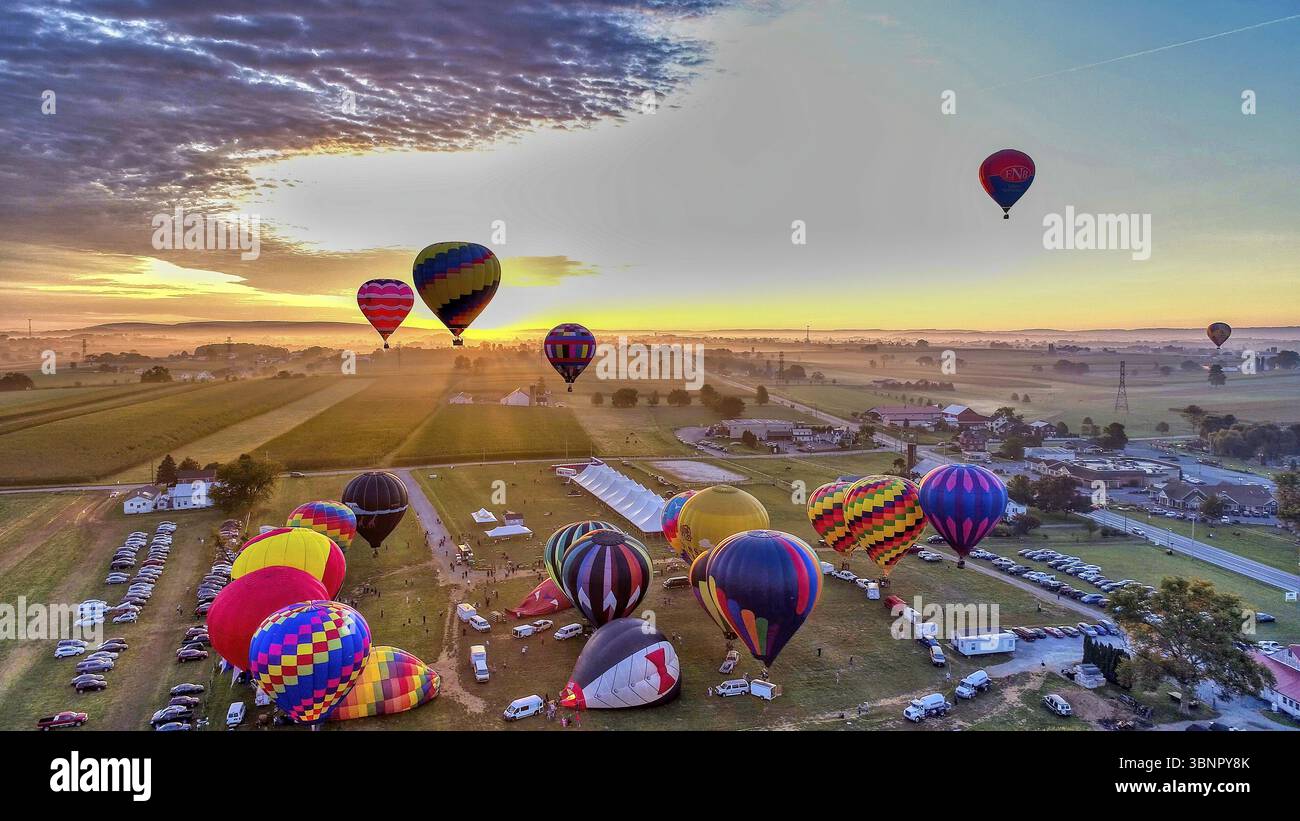 Bolloni ad aria calda che decolla all'alba a un caldo Air Balloon Festival in una mattinata mistosa Foto Stock