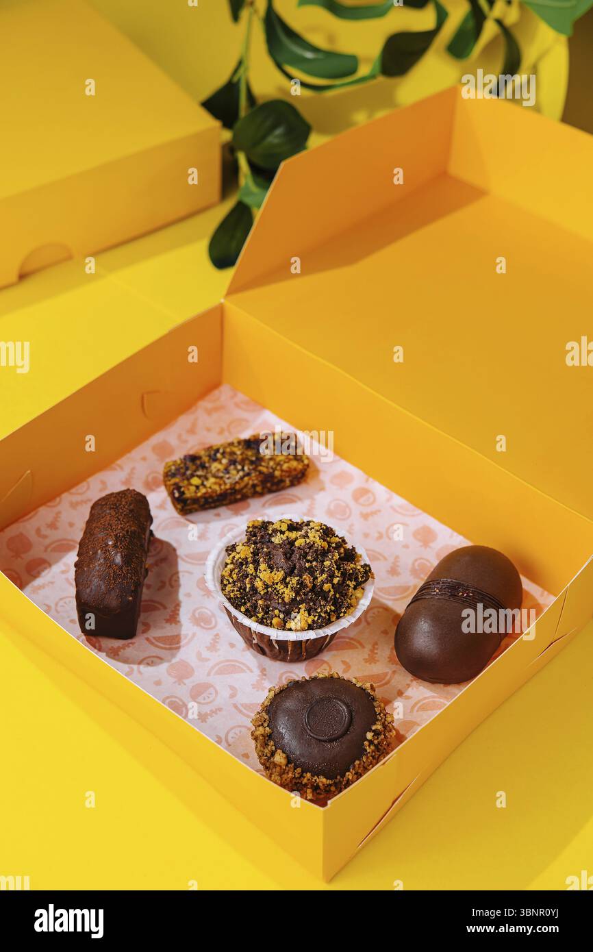 Regali di Natale con torte diverse su scatola gialla Foto Stock