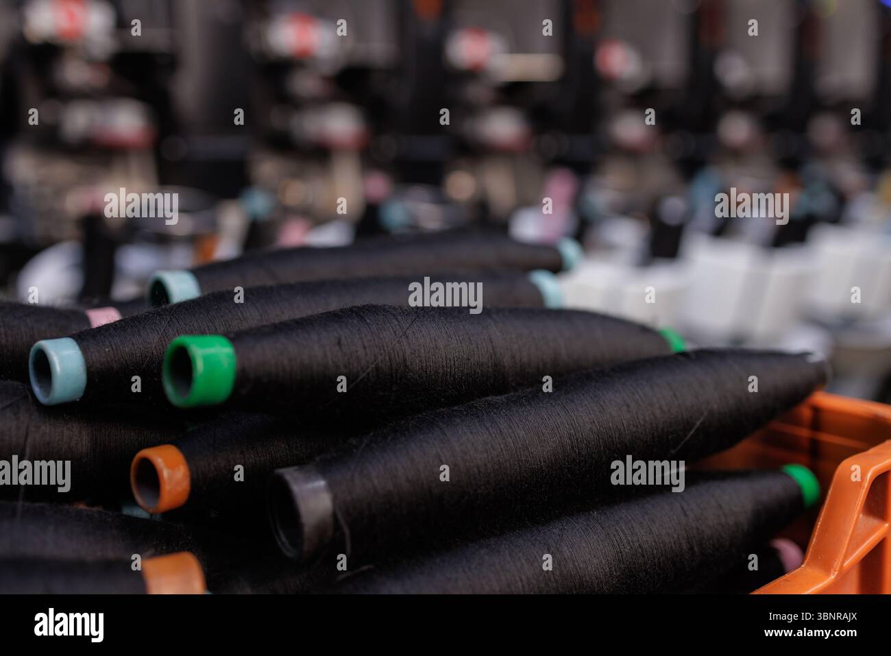 Primo piano di bobine con filettatura nera sulla linea di produzione di filati nel moderno processo di produzione dell'industria tessile Foto Stock