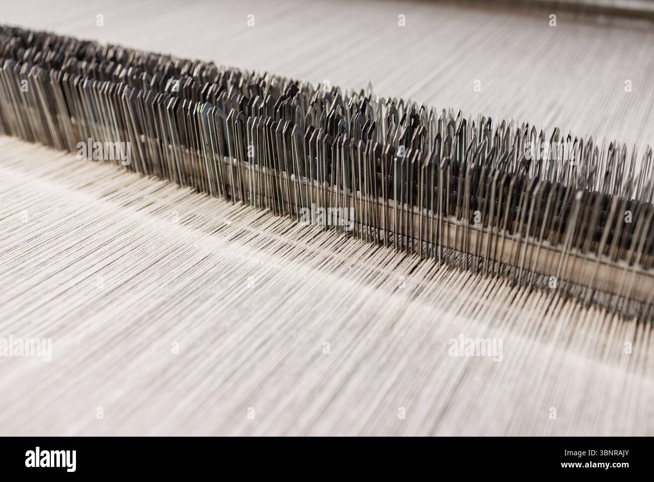 Vista macro dettagliata della tessitura del tessuto di lana del telaio della fabbrica con precisione in un moderno impianto tessile industriale Foto Stock