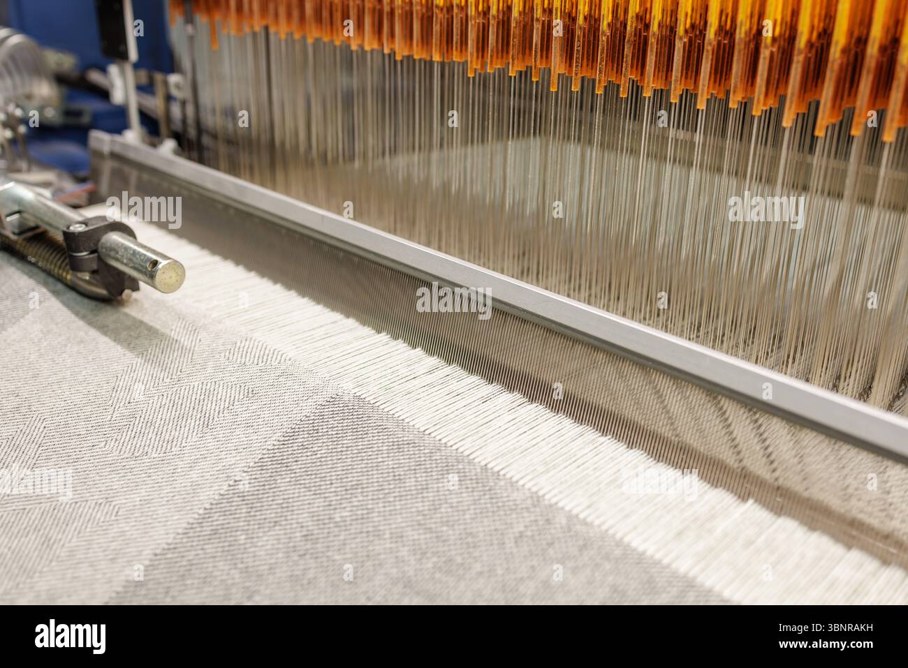 Primo piano del tessuto di lana di tessitura del telaio industriale in una moderna fabbrica tessile con processo di produzione automatizzato Foto Stock