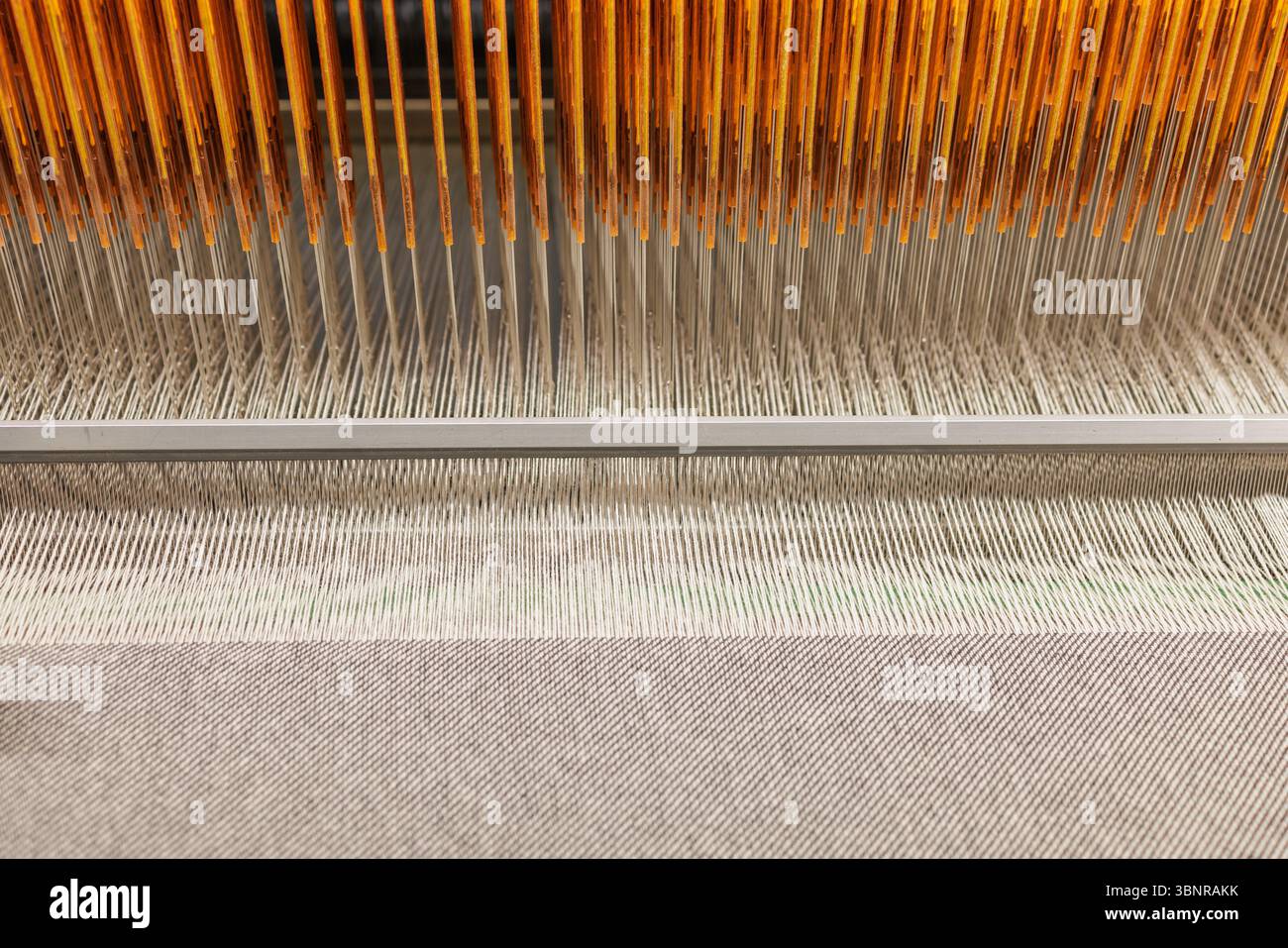 Vista macro del tessuto di lana di tessitura del telaio industriale in una moderna fabbrica tessile che mostra un processo di produzione preciso Foto Stock
