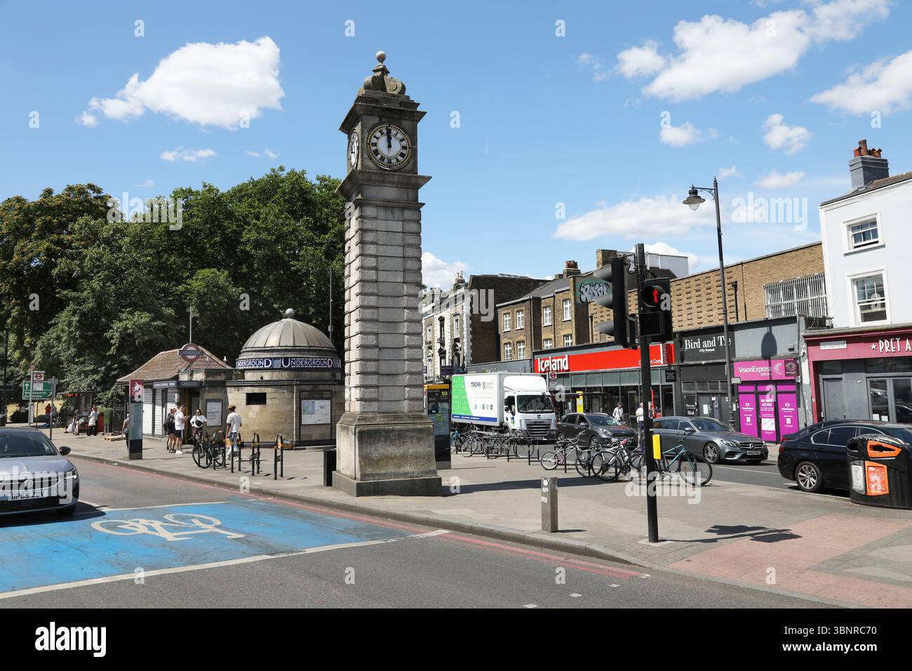 Clapham, Londra, Regno Unito. Incrocio tra Long Road e Clapham Common South. Mostra la torre dell'orologio e l'ingresso principale della stazione della metropolitana di Clapham Common. Foto Stock Clapham, Londra, Regno Unito. Incrocio tra Long Road e Clapham Common South. Mostra la torre dell'orologio e l'ingresso principale della stazione della metropolitana di Clapham Common. Foto Stock