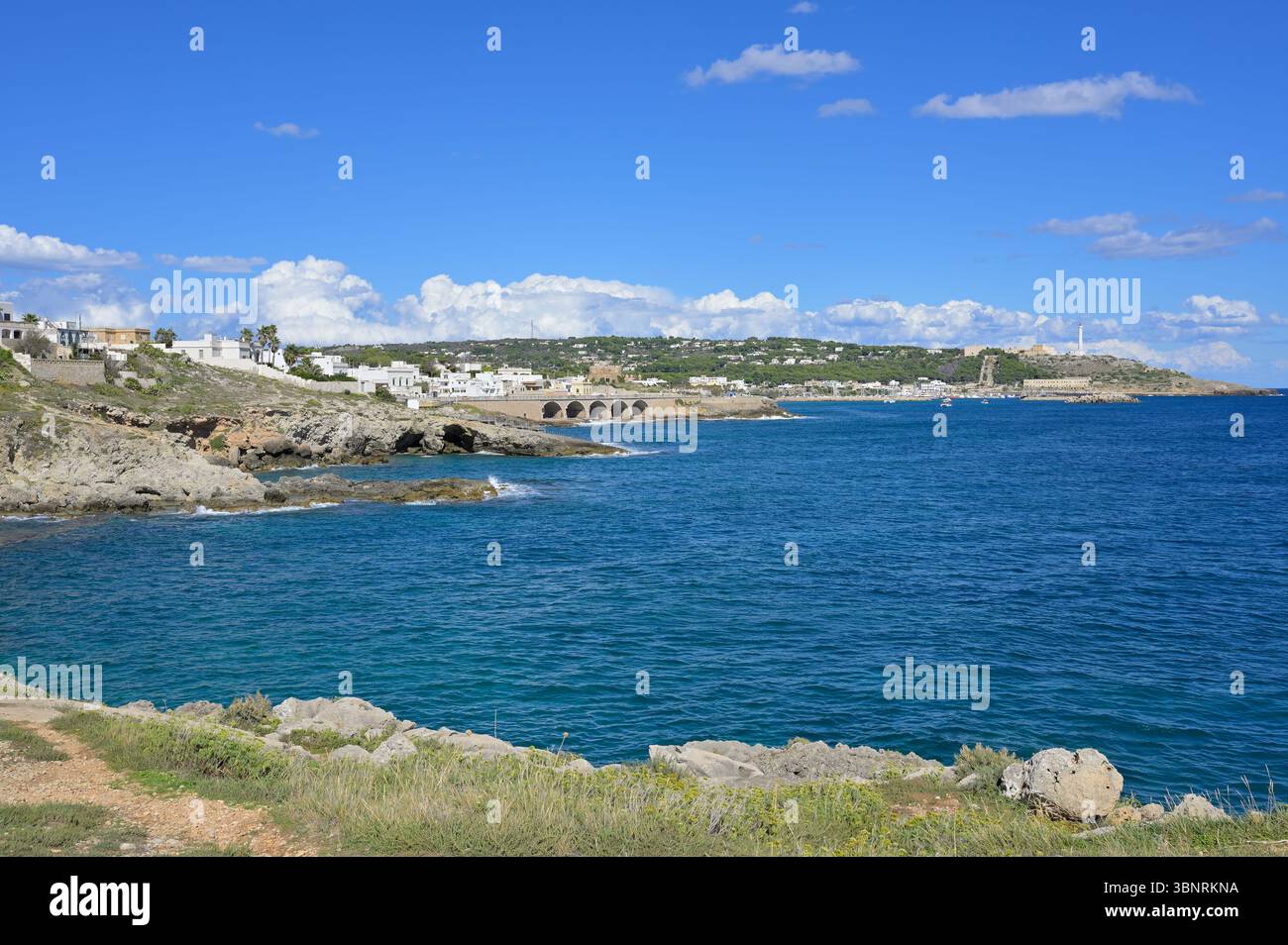Vista dalla costa di Punta Ristola verso la destinazione estiva di Santa Maria di Leuca, contro il cielo azzurro con nuvole sparse. Puglia, Italia meridionale. Foto Stock