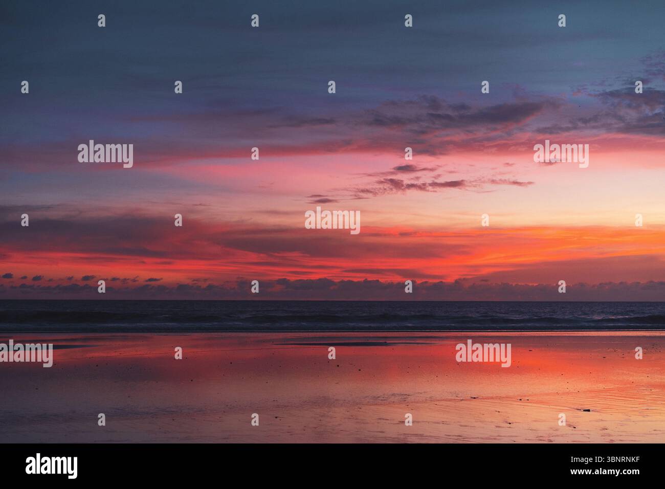 Tramonto vivido su una spiaggia riflettente senza persone presenti Foto Stock