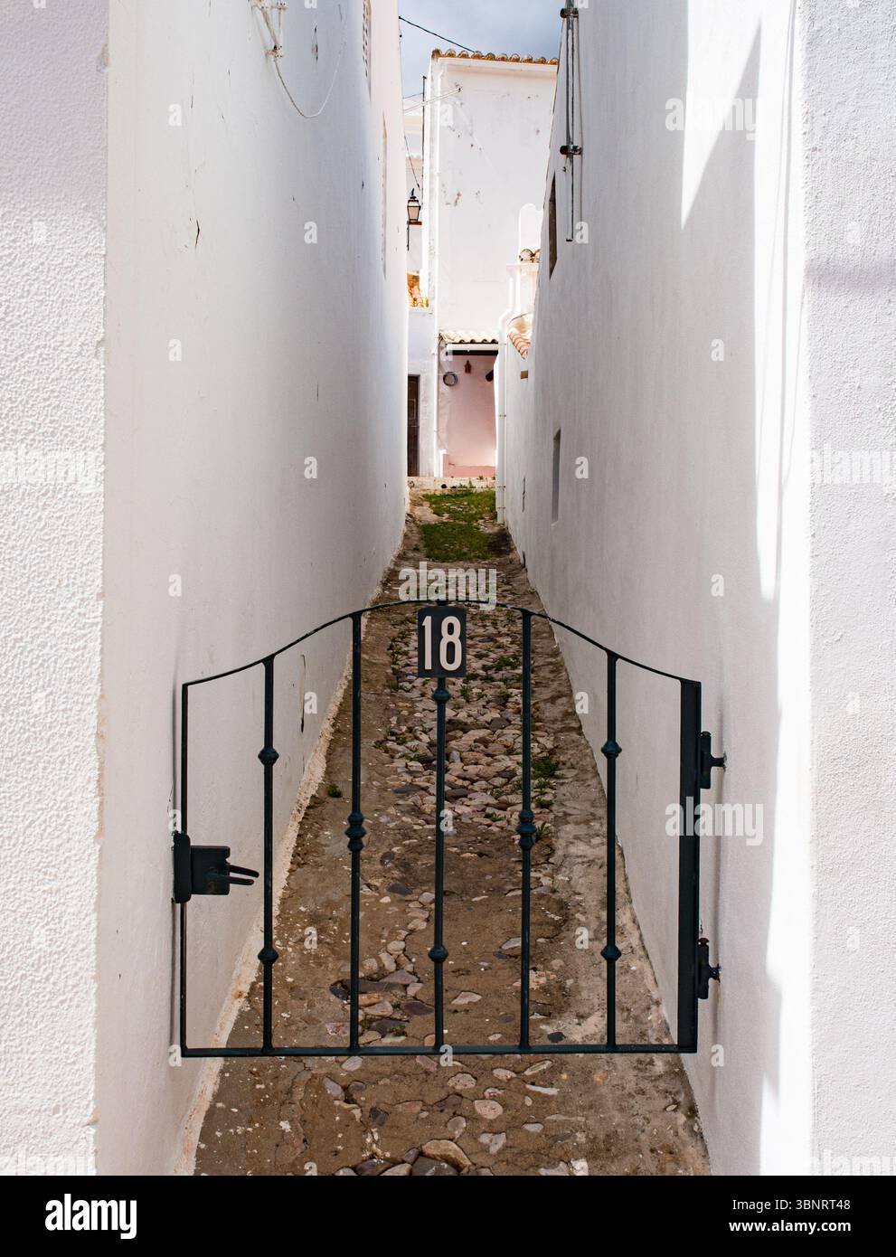 Vicolo stretto con cancello in ferro battuto nero e pareti dipinte di bianco, Algarve, Portogallo. Foto Stock