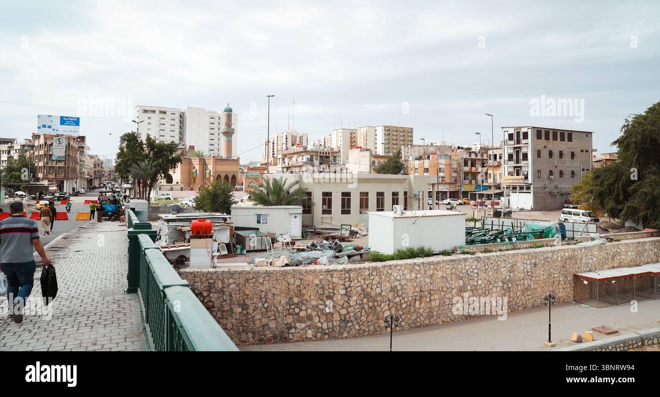 Le persone camminano attraverso un vivace quartiere di Baghdad, evidenziando la costruzione urbana e la vivace attività di strada. Foto Stock