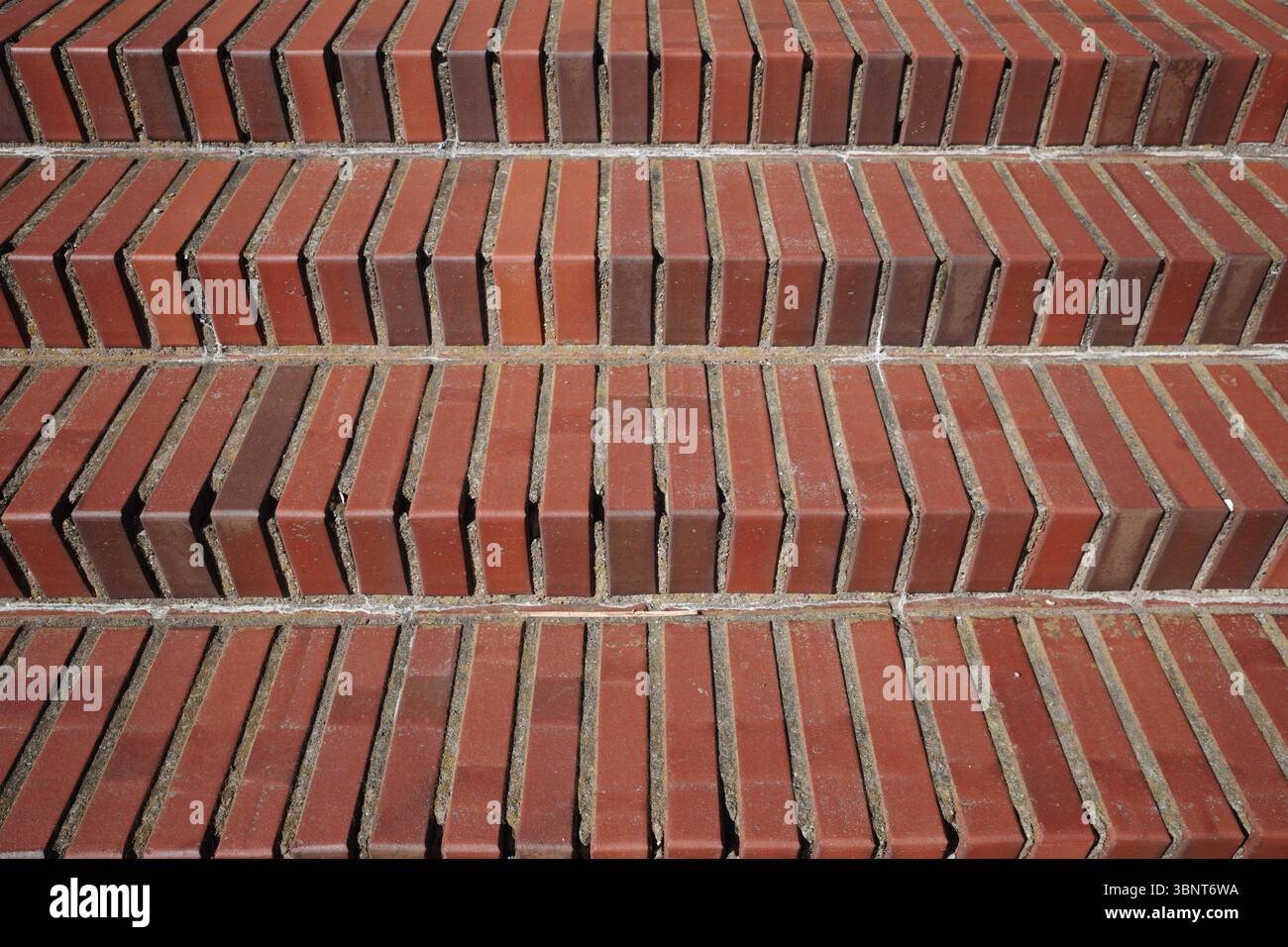 Una vista ravvicinata e diretta delle scale in mattoni rossi. Le linee orizzontali ripetute dei gradini creano una forte ripetizione geometrica e una ricca a Foto Stock
