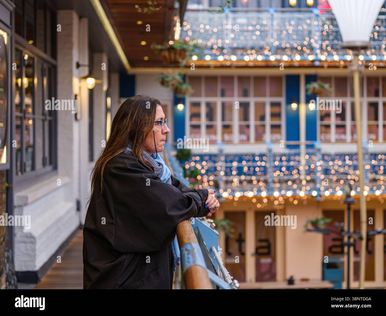 Regno Unito, Londra, 07 luglio 2025. Donna che indossa una giacca invernale blu sfogliando i portapacchi d'abbigliamento vintage all'interno di un negozio di seconda mano a Londra, surrogato Foto Stock