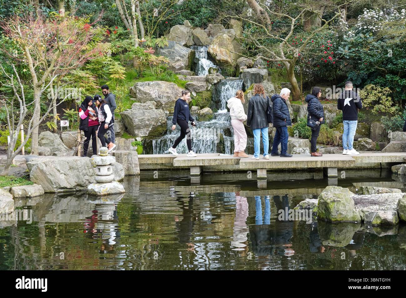 Persone che visitano la cascata del Giardino di Kyoto in Holland Park, Londra, Inghilterra Regno Unito Regno Unito Foto Stock