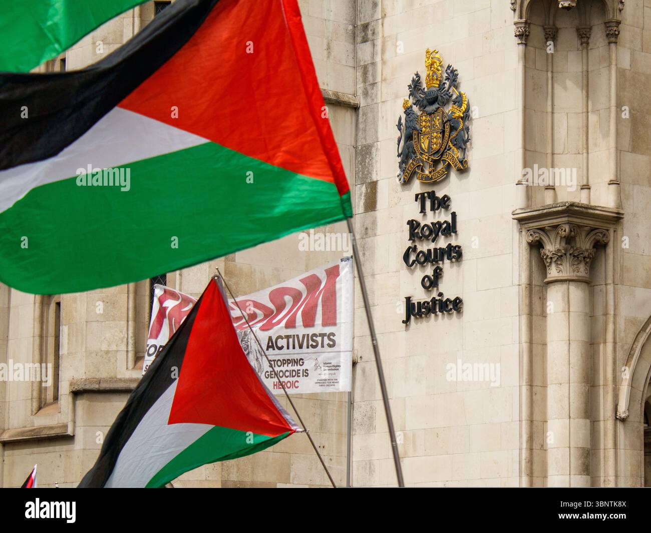 Londra, Inghilterra, 4 luglio 2025. Una bandiera della Palestina può essere vista durante una protesta contro la Palestina accanto a un emblema della Royal Courts of Justice. Questa manifestazione si sta svolgendo mentre i rappresentanti della Palestina Action sono dentro a chiedere un sollievo temporaneo. Se il soccorso non sarà concesso, l’azione palestinese diventerà un’organizzazione terroristica a mezzanotte. Foto Stock
