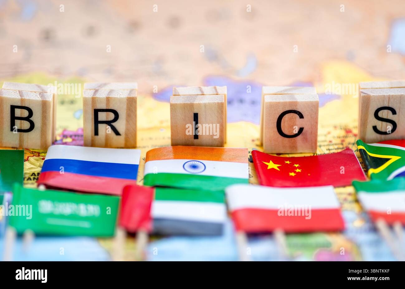 Un concetto BRICS con tessere di lettere e bandiere di piccoli paesi sullo sfondo di una mappa del mondo. Foto Stock