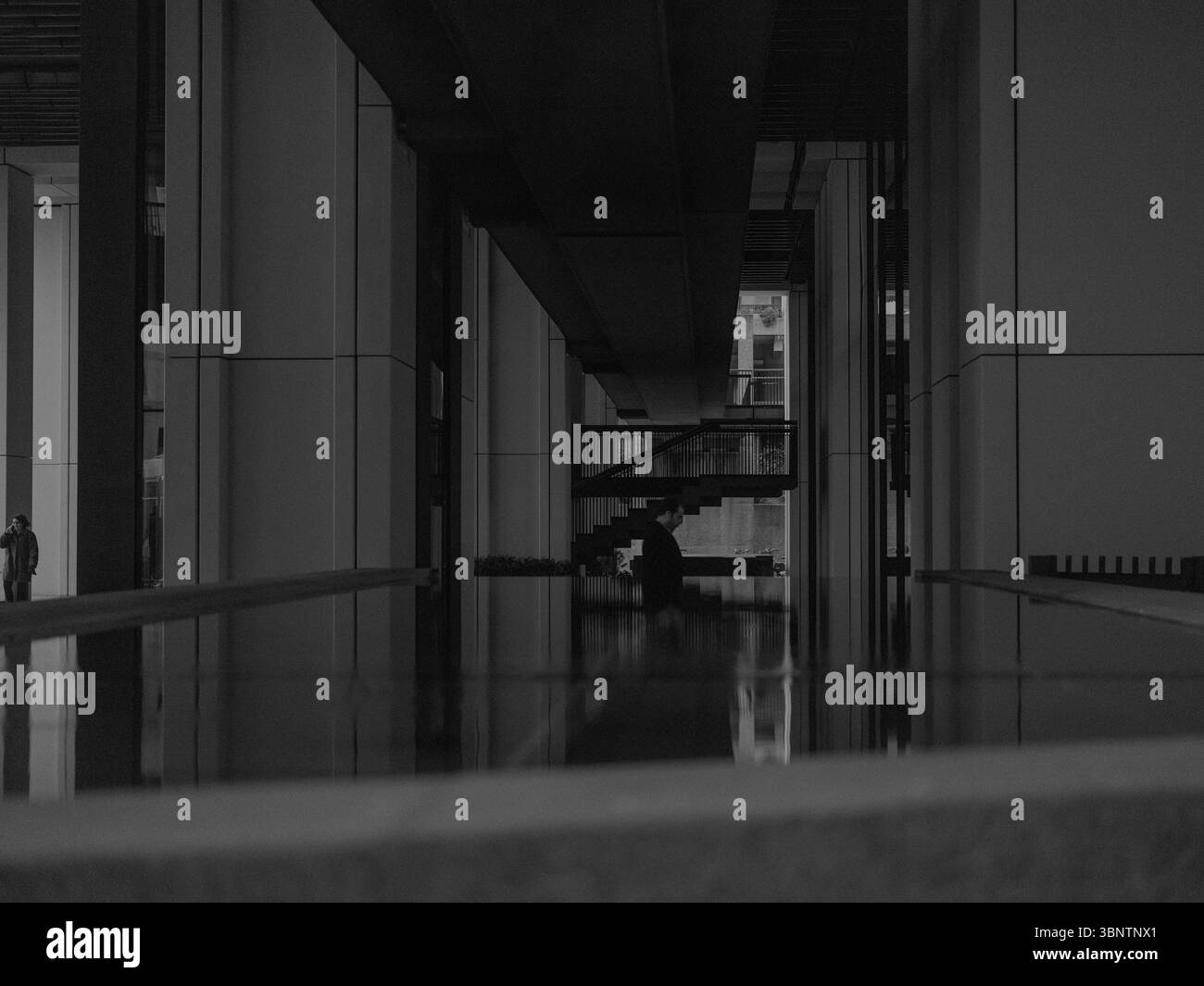 Londra, Regno Unito, 11 dicembre 2024. Corridoio poco illuminato in un edificio aziendale nel quartiere finanziario, caratterizzato da ombre forti e simmetria geometrica Foto Stock