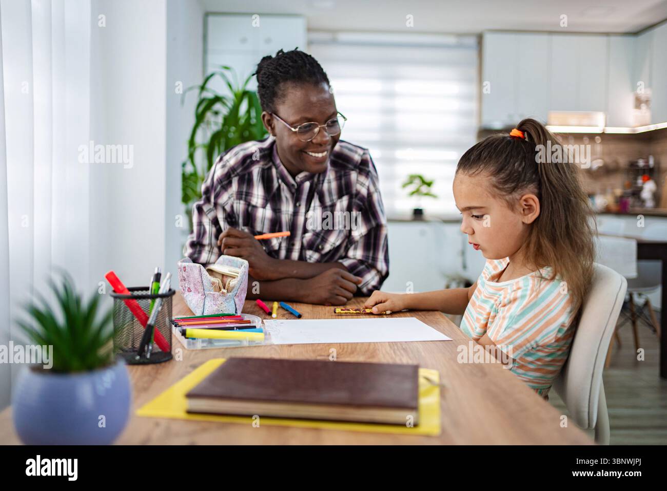 Momento di apprendimento creativo tra un mentore e un bambino a casa Foto Stock