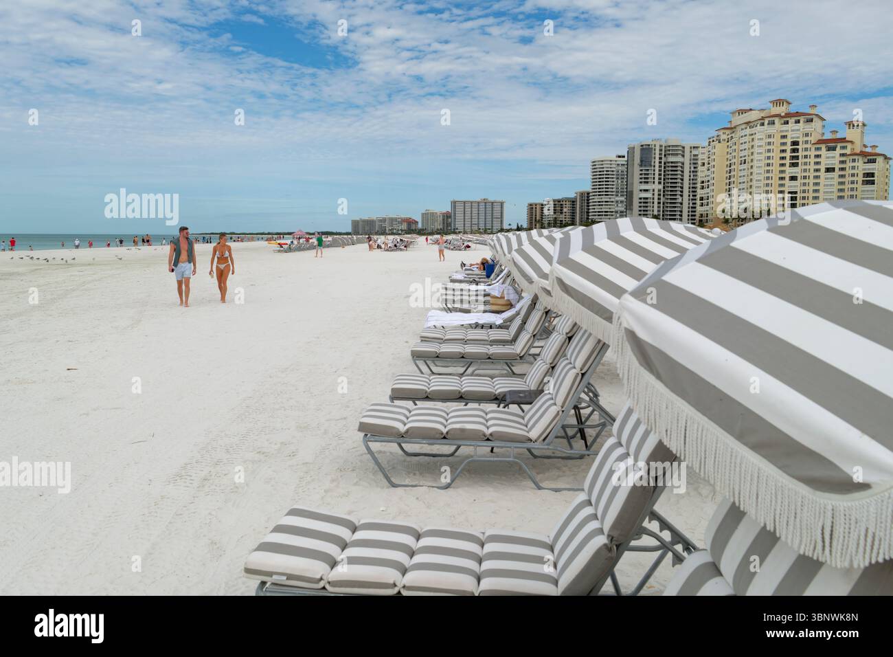 Una coppia di giovani adulti che cammina su una spiaggia di sabbia bianca, Marco Island, Florida Foto Stock