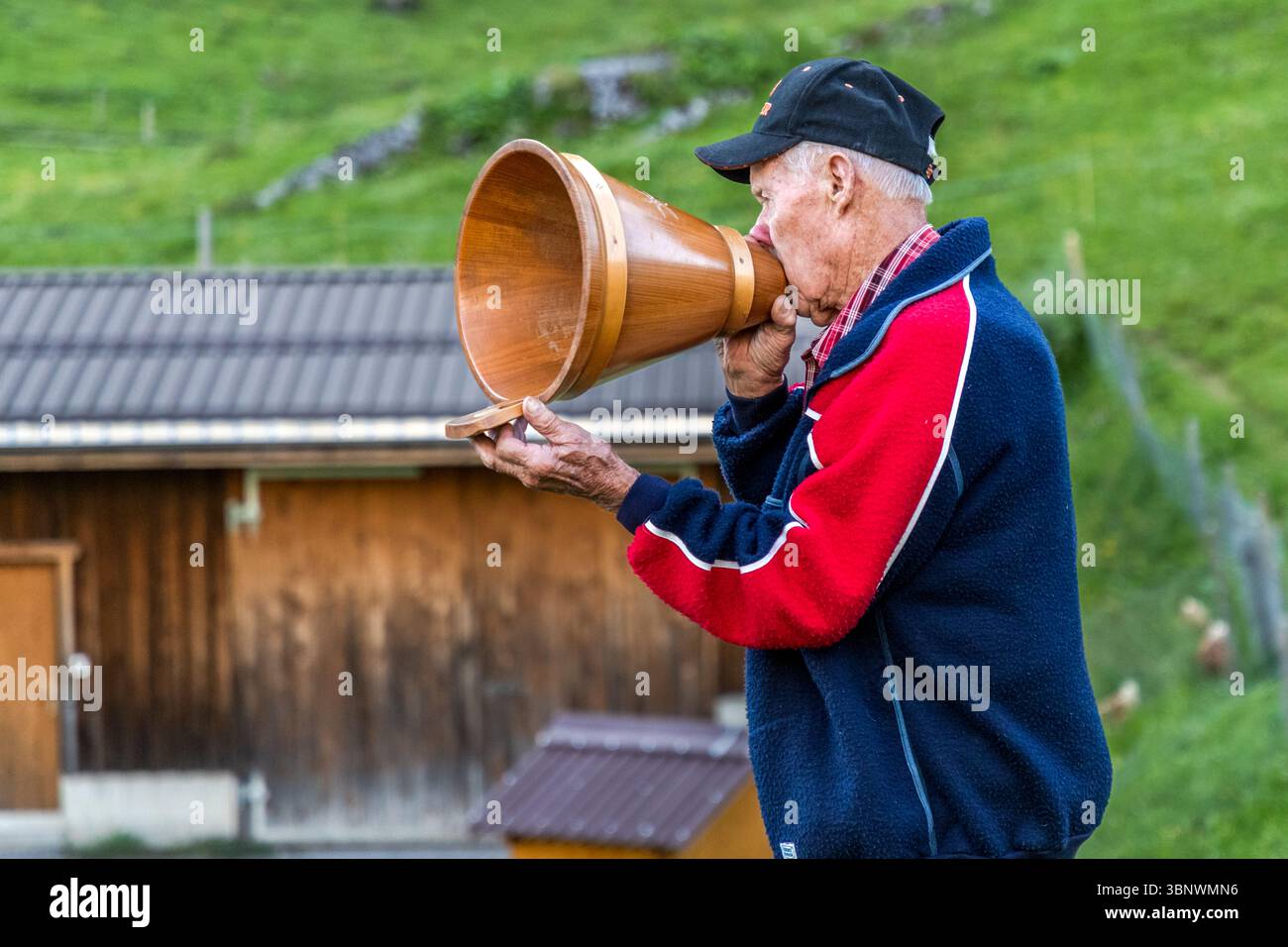 Sepp Zurfluh prese il controllo dell'Alpe di Hobiel da suo padre nel 1970. Ha già trascorso 69 estati qui. La sera, chiama l'Alpsegen, noto anche come "Betruf", in tutte e quattro le direzioni per una protezione completa contro il pericolo. Utilizza un imbuto di legno per il latte (folli) per amplificare la sua voce. Rituale serale nel paesaggio alpino all'Hobiel-Alp, vicino Engelberg, Svizzera. Il membro della famiglia più anziano esegue la tradizionale chiamata alla preghiera di fronte a tutti i presenti. Questa tradizione mostra la combinazione di profonda pietà e la natura impressionante delle Alpi svizzere. Hobiel, Engelberg, Uri Foto Stock