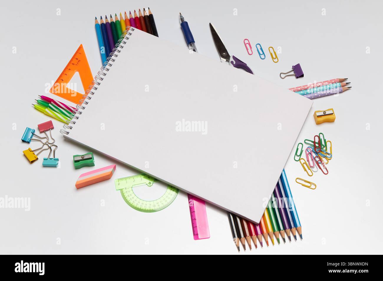 Cancelleria colorata e forniture da disegno circondano un bozzetto vuoto su una superficie pulita, creando un'atmosfera invitante per l'arte e la creatività durante il periodo Foto Stock