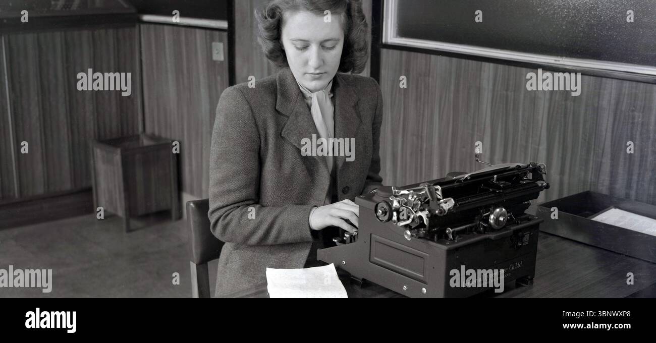 Anni '1940, storica, una segretaria, una giovane donna elegante, abito di lana e sciarpa da collo, in un ufficio, seduta a una scrivania con una macchina da scrivere, realizzata dalla Imperial Typewriter Co di Leicester, Inghilterra, Regno Unito, scrivendo un quaderno con stendardo. Foto Stock