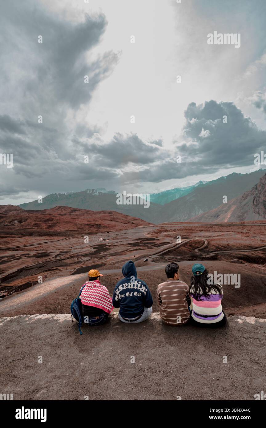 Un gruppo di amici intimi seduti al punto panoramico di Langza, immersi nelle maestose vedute dell'Himalaya, celebrando l'amicizia, la solidarietà, i ricordi di viaggio. Foto Stock
