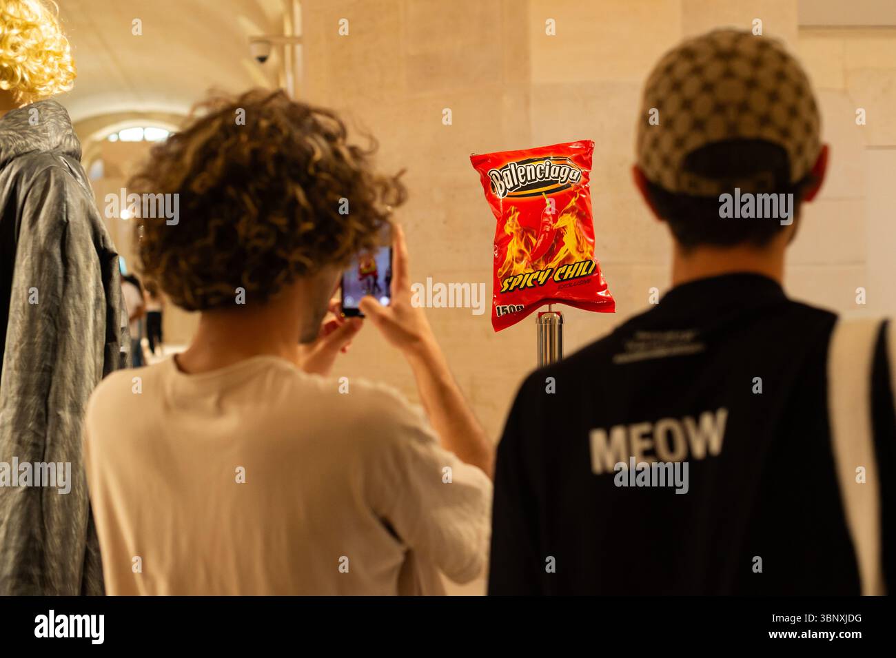 Parigi, Île-de-France / Francia - 3 luglio 2025: Un visitatore fotografa una borsa di chip "Spicy Chili" firmata Balenciaga in mostra alla fiera della moda. Foto Stock