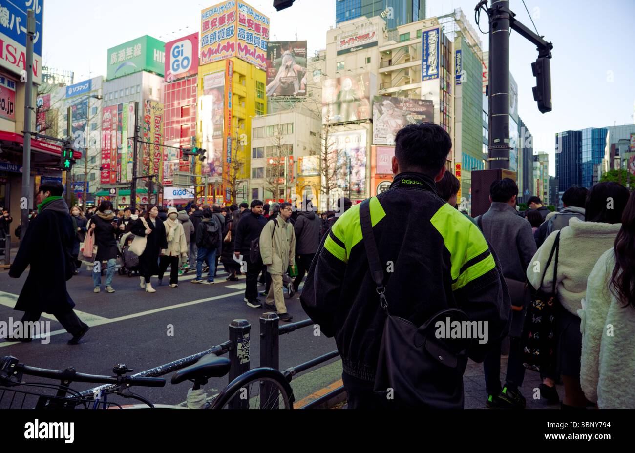 La folla riempie un colorato attraversamento di Akihabara, con luminosi cartelloni pubblicitari anime e la vita cittadina in pieno svolgimento Foto Stock