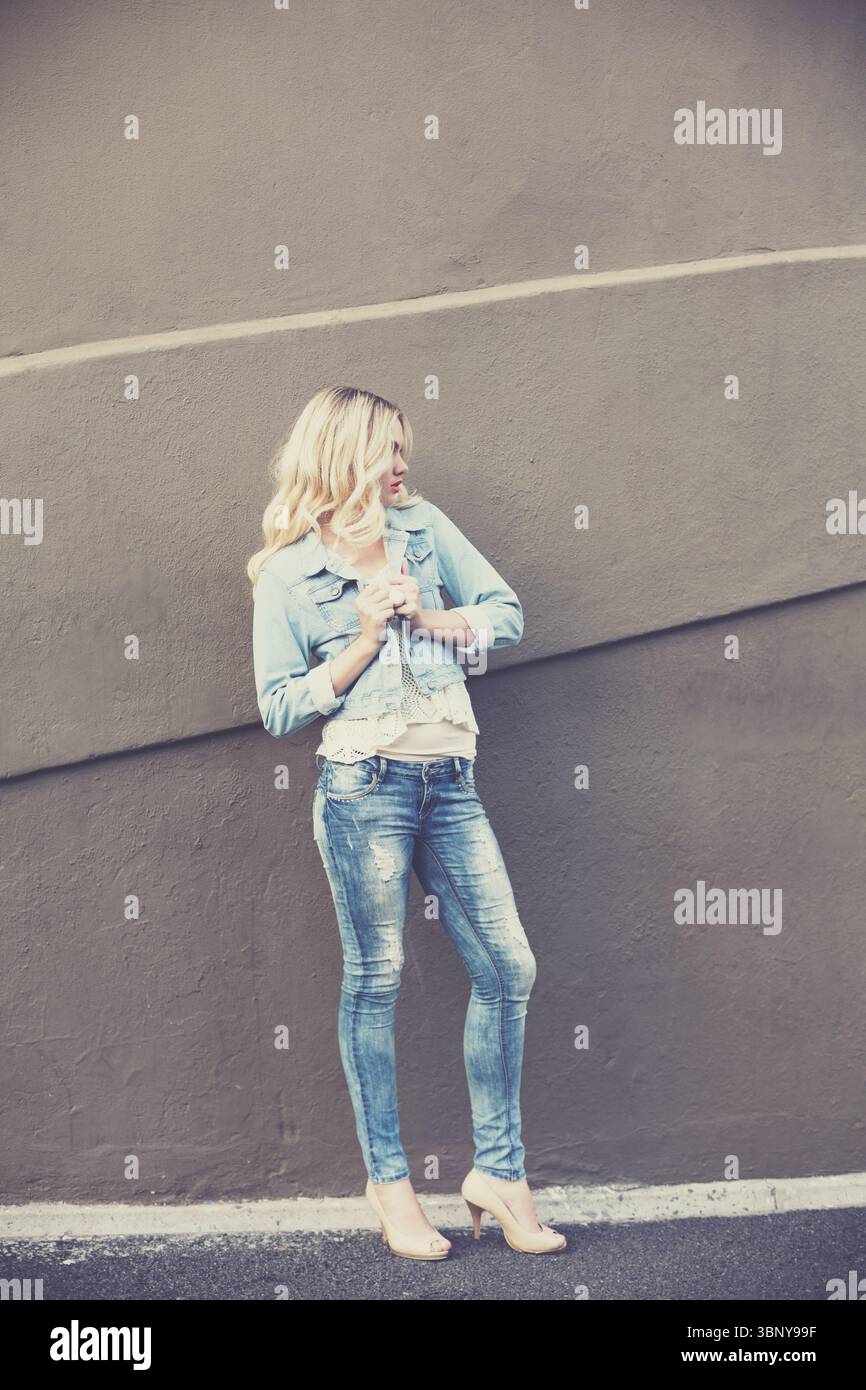 Giovane donna in piedi contro il muro Foto Stock