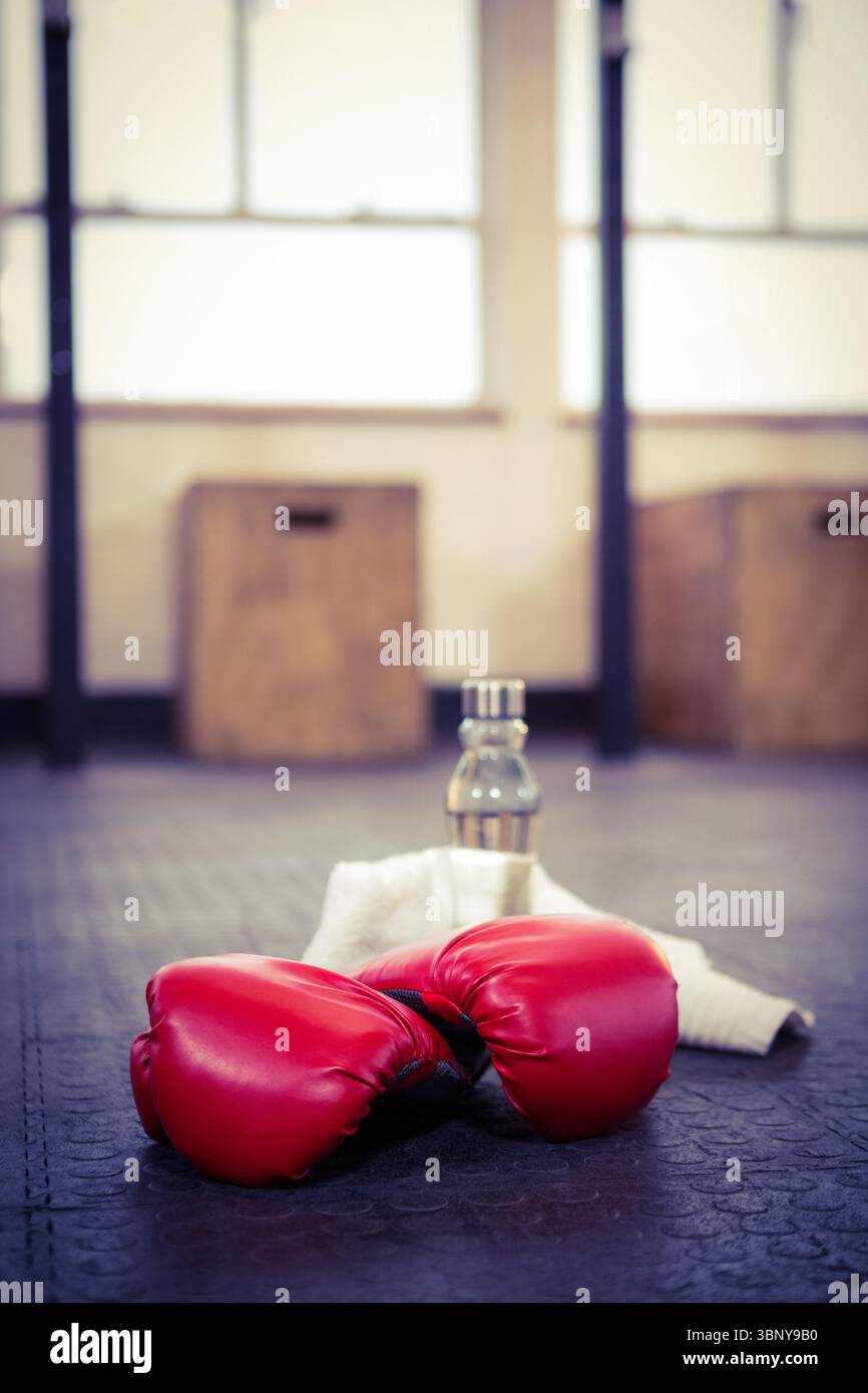 Guanti da boxe con bottiglia sul pavimento in palestra Foto Stock