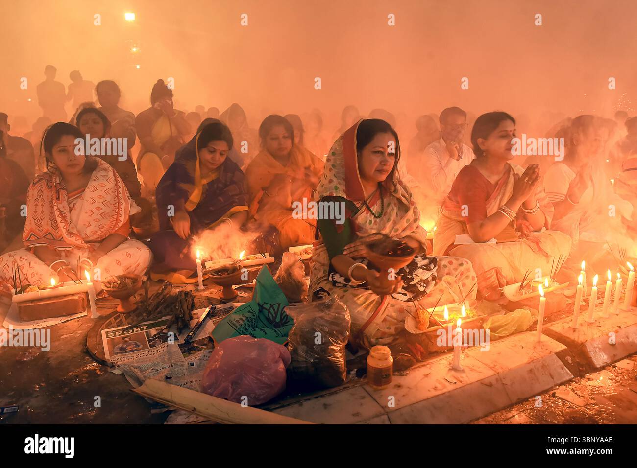 La gente partecipa a una preghiera chiamata Rakh festival, circondata da incenso fumo e illuminazione soffusa, creando un'atmosfera serena. Foto Stock