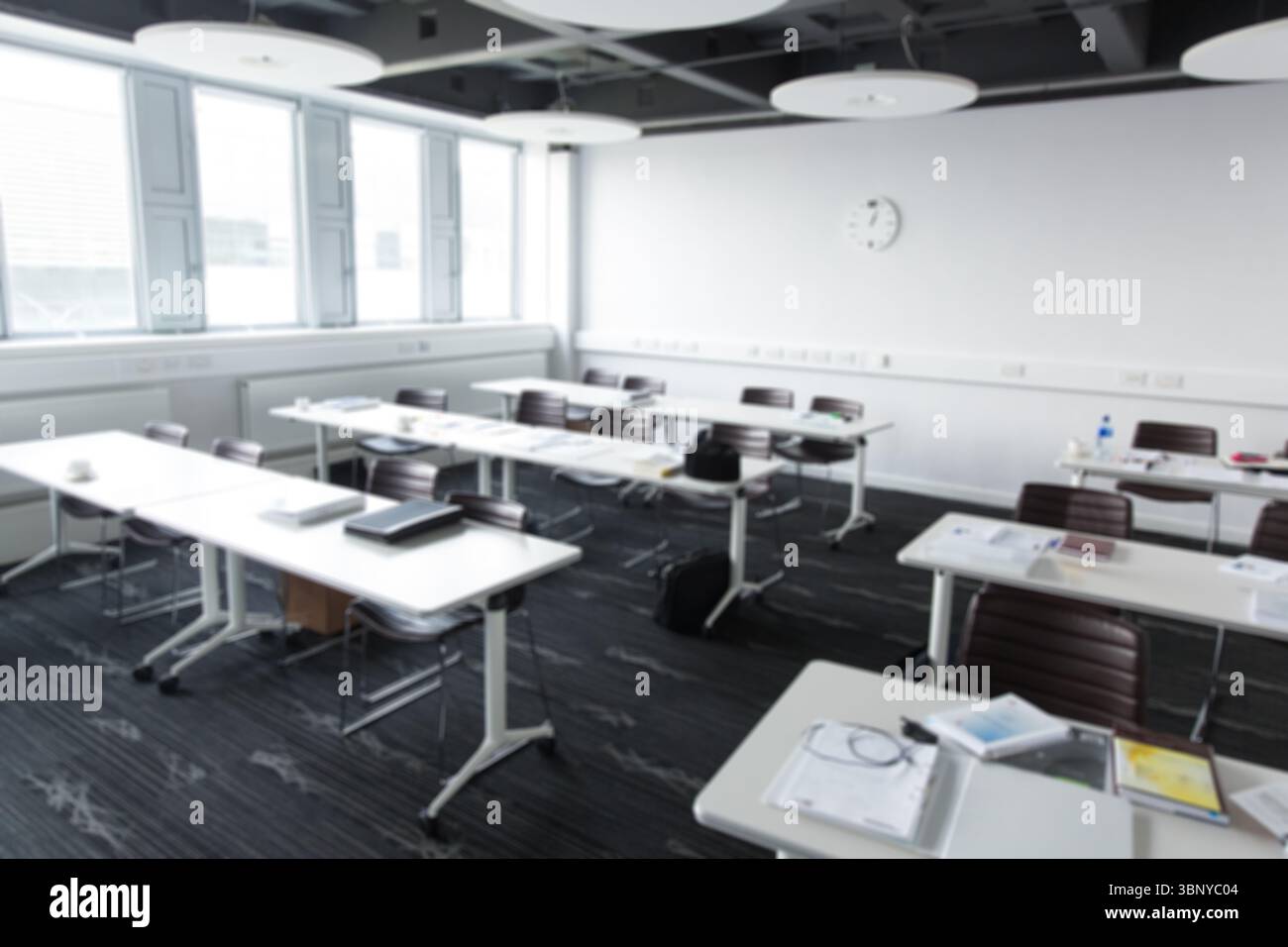 Tavoli bianchi e sedie marroni creano una disposizione per conferenze dal design piatto con notebook e penne Foto Stock