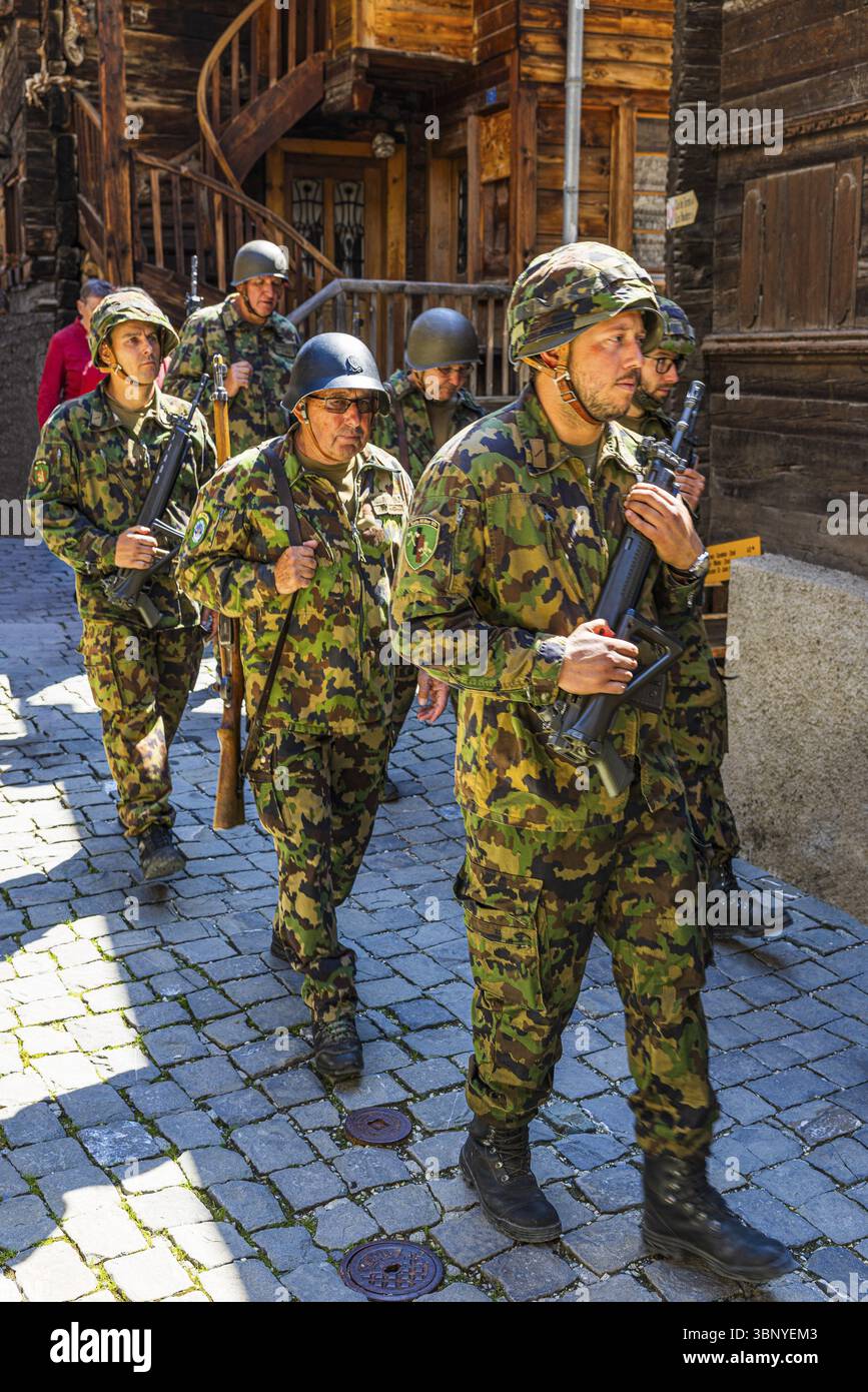 I soldati della società del patrimonio locale accompagnano la processione del Corpus Christi, il centro storico della città, Grimentz, la Val d'Anniviers, le Alpi Vallese, Cantone Foto Stock